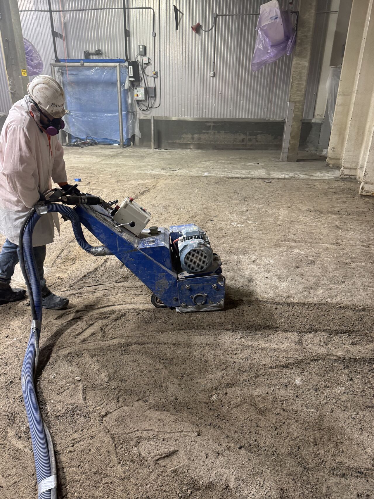 Crew member grinding a blast freezer floor during surface preparation