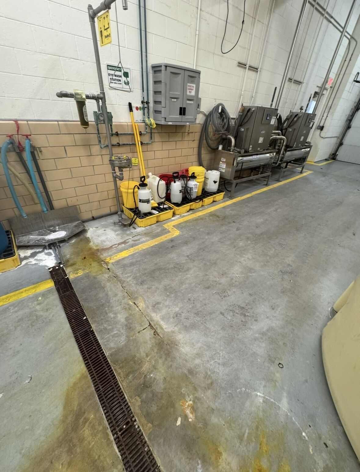 Chemical storage area before — worn concrete floor with staining, cracking, and chemical containers