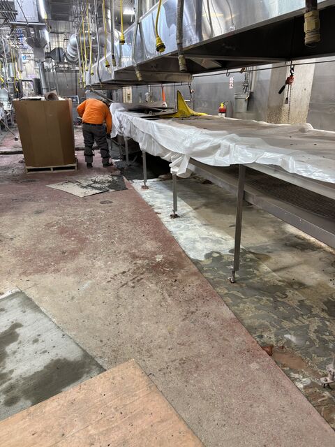 SaniCrete crew working beside protected dairy processing conveyors during brick removal and prep