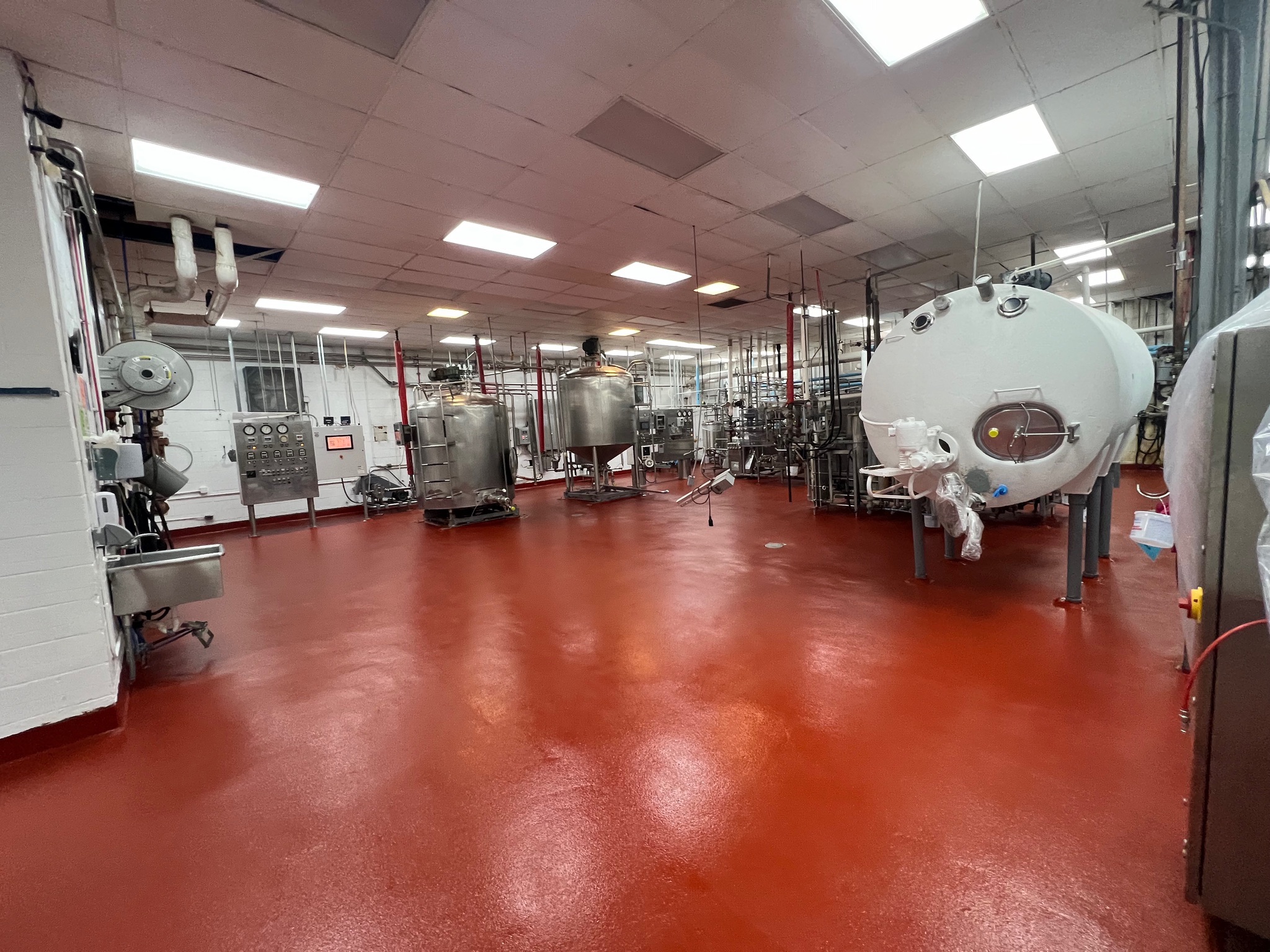 SaniCrete red flooring in a dairy processing facility with pasteurization tanks and stainless steel equipment