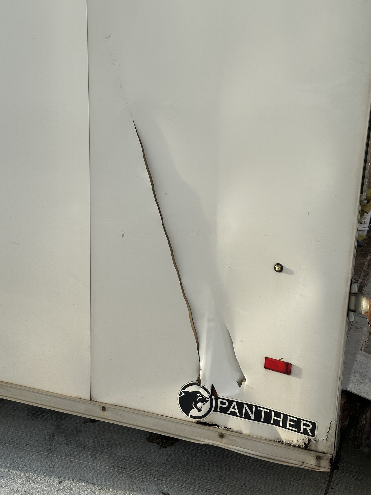 Long tear and impact damage along the side of a jobsite trailer after the tornado