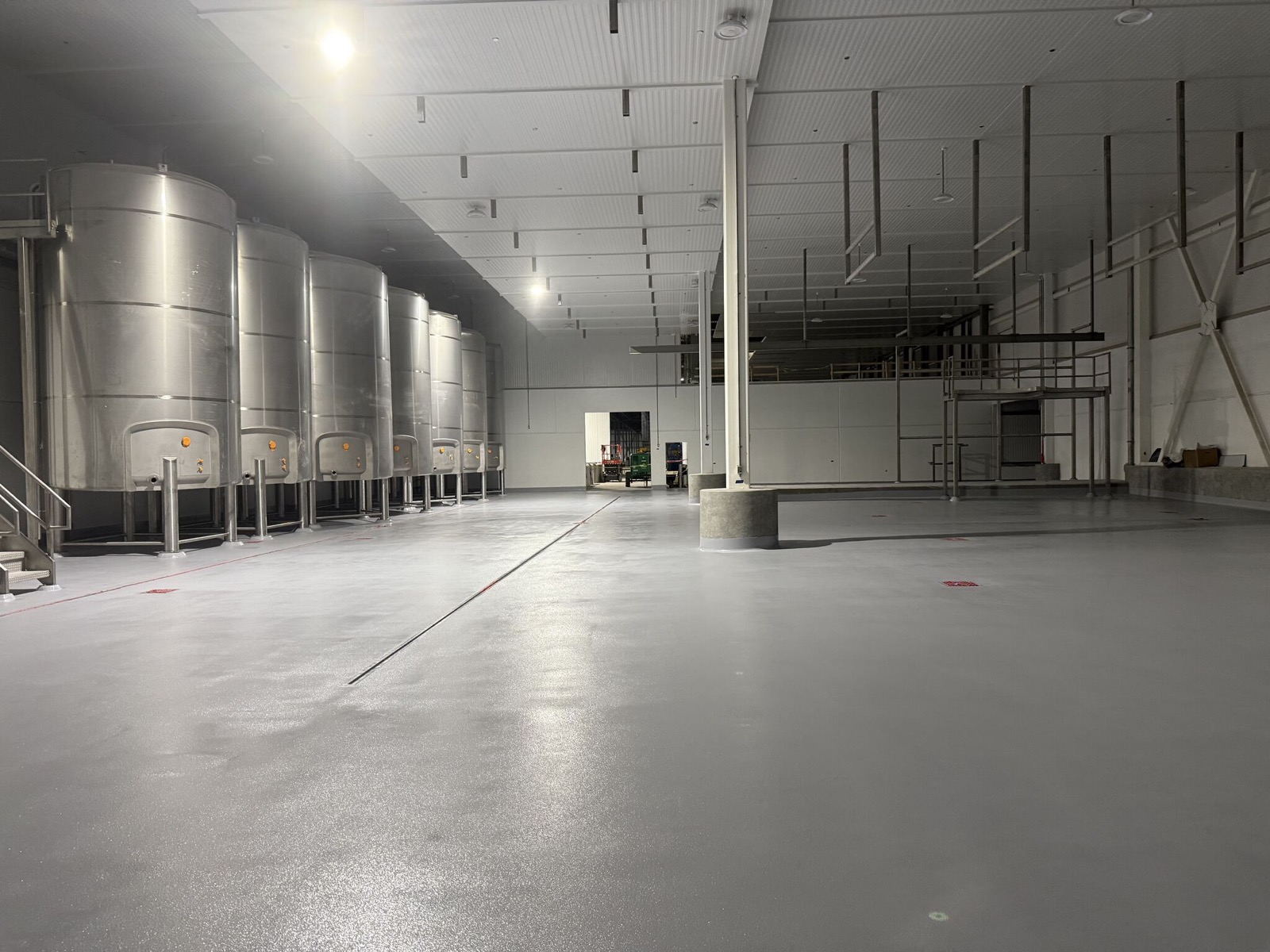 Finished gray floor throughout a new dairy processing area with stainless steel tanks