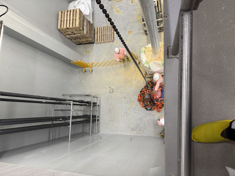 Overhead view of crew guiding equipment through elevated floor opening
