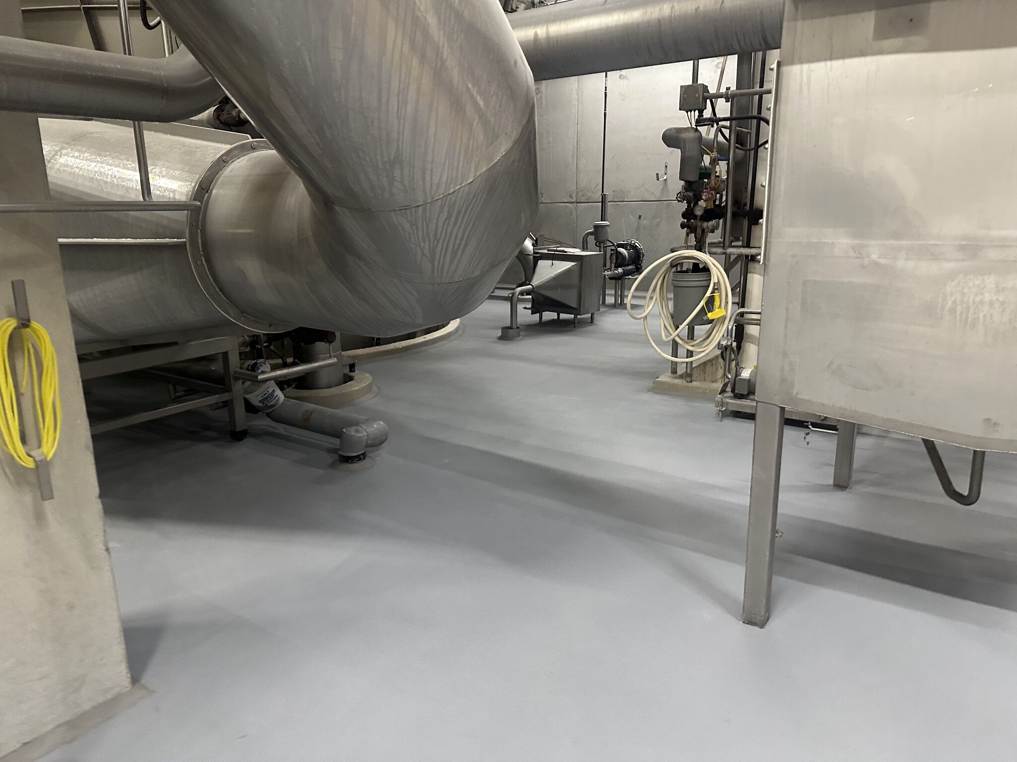 Completed SaniCrete STX resinous floor with same equipment angle showing clean gray finish