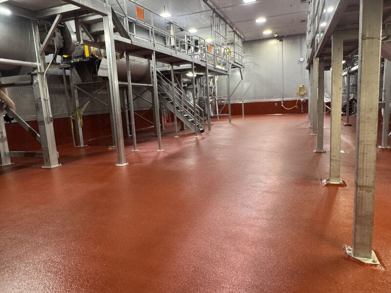 Completed red-orange floor restoration with cove base and processing equipment