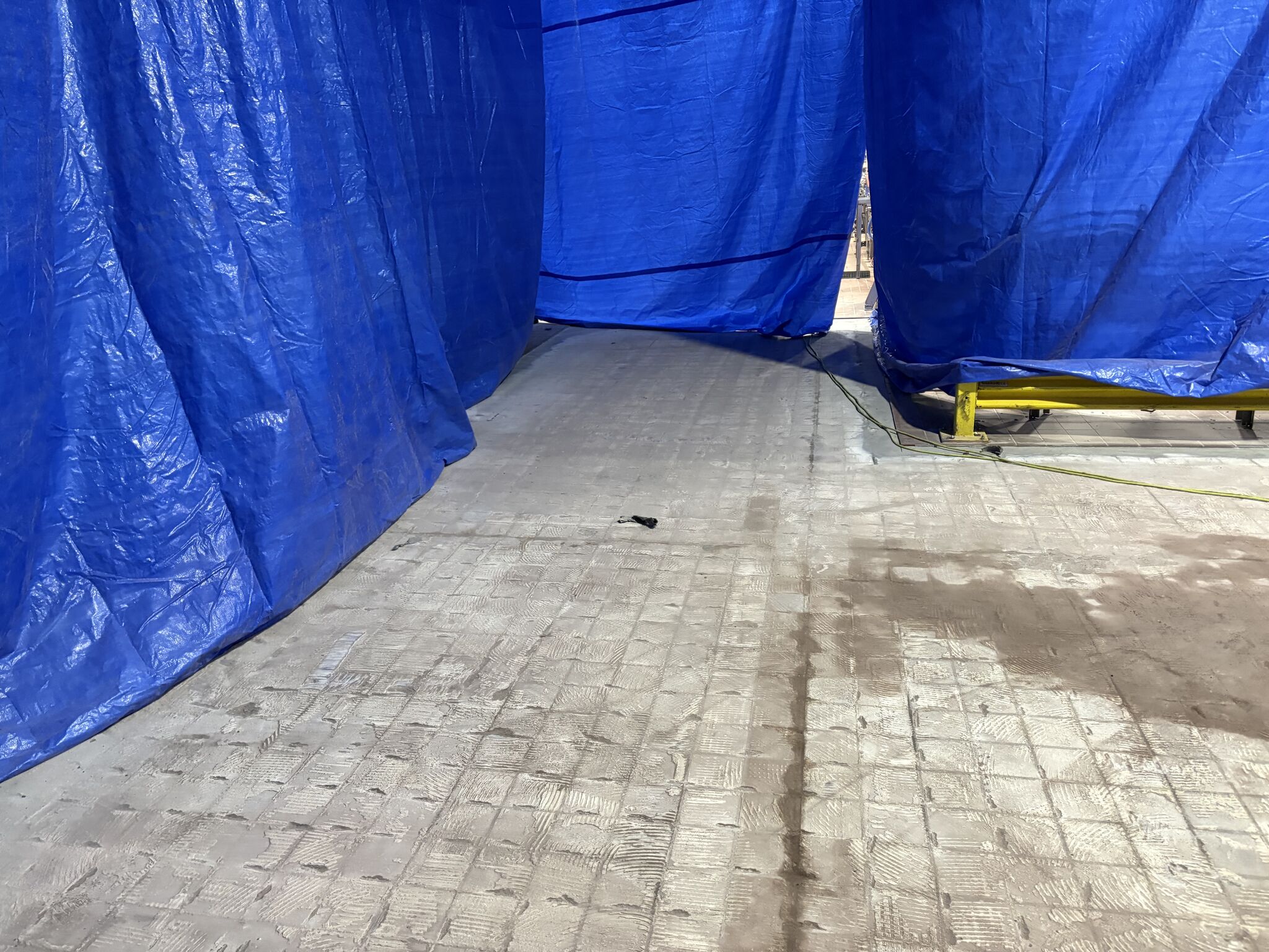 Food plant floor after failed tile was removed, showing adhesive marks and prepared substrate