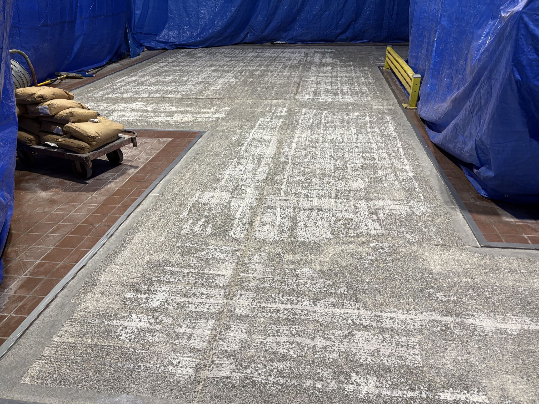 Scarified food plant floor with material staged beside the repair area before SaniCrete STX installation