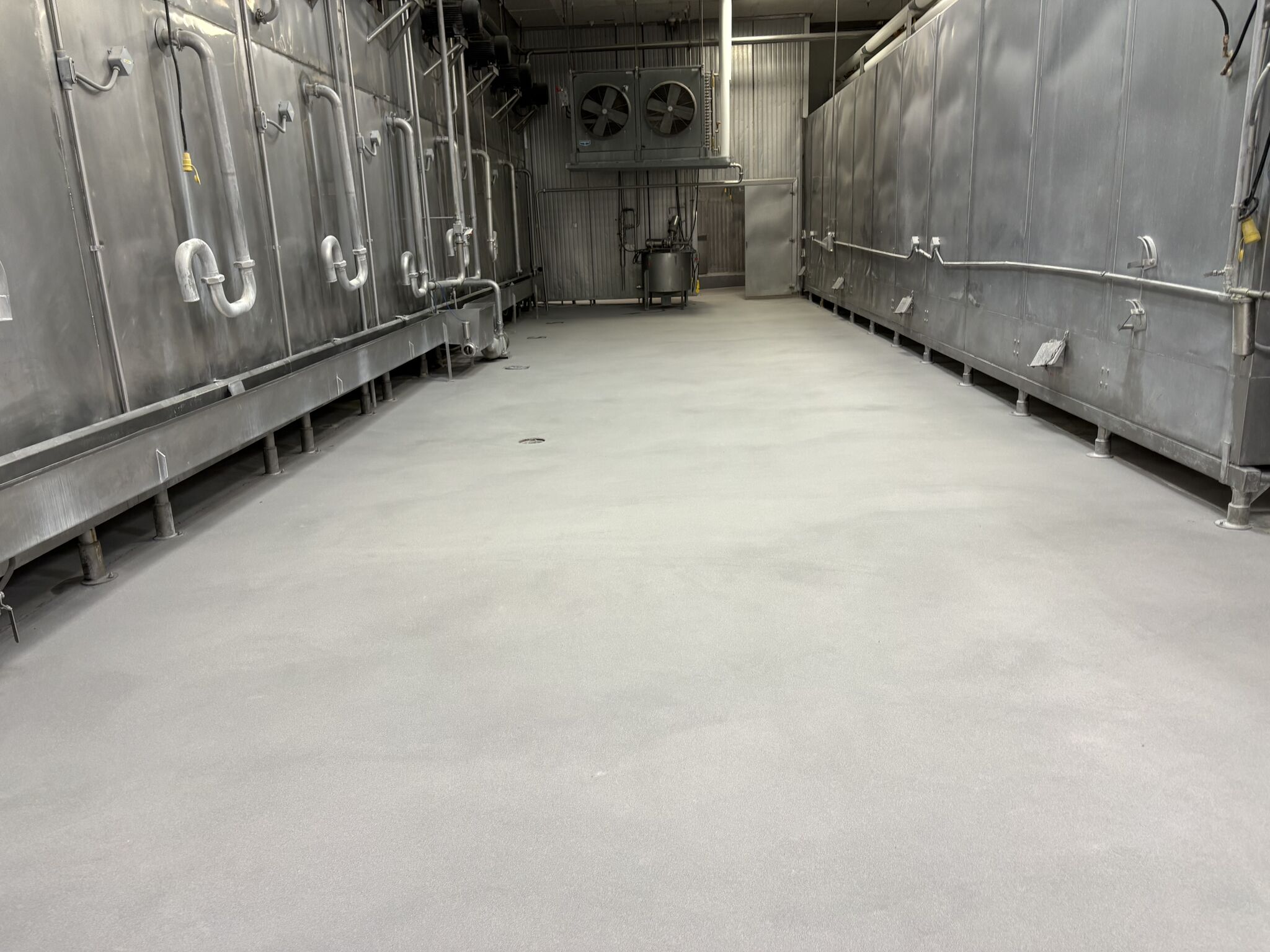 Completed SaniCrete STX floor in processing corridor between stainless steel equipment lines