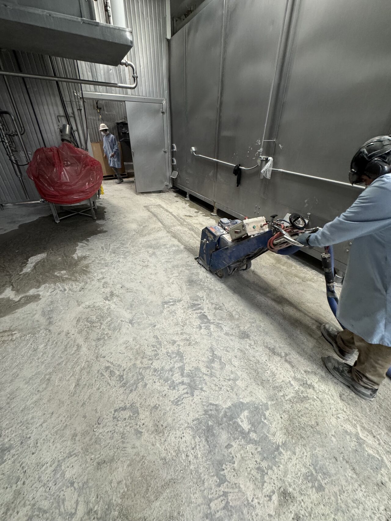SaniCrete crew member scarifying concrete floor with grinding equipment in meat processing facility
