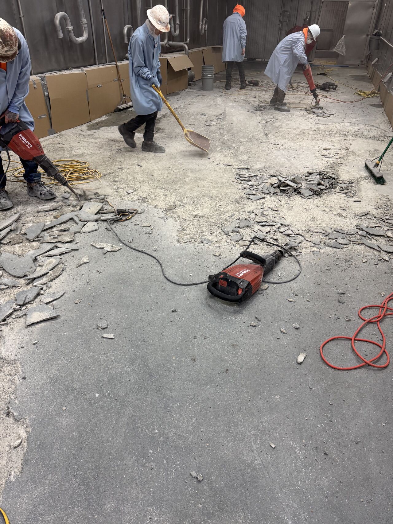 SaniCrete crew using jackhammers and shovels to remove layers of failed floor coatings in meat processing facility