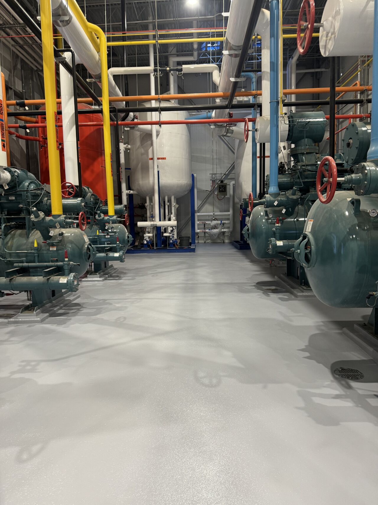 Looking down the aisle between compressor rows — seamless SaniCrete floor still in excellent condition after one year