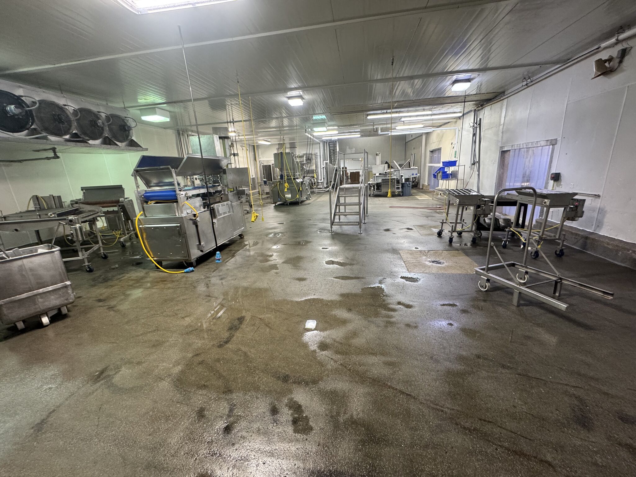 Bare wet concrete floor in processing area with food production equipment before SaniCrete installation