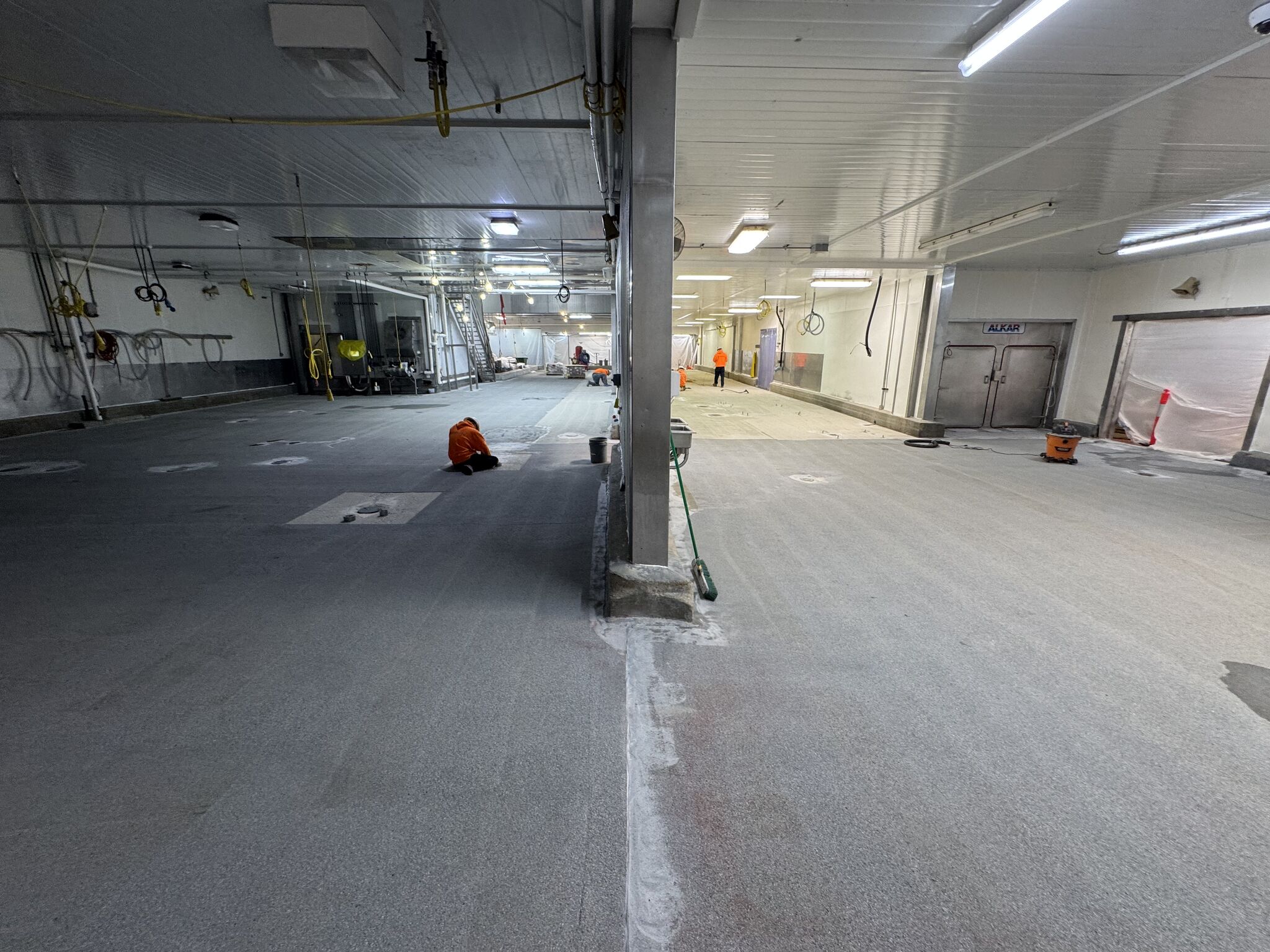 SaniCrete crew members hand-troweling base coat on oven room floor during installation