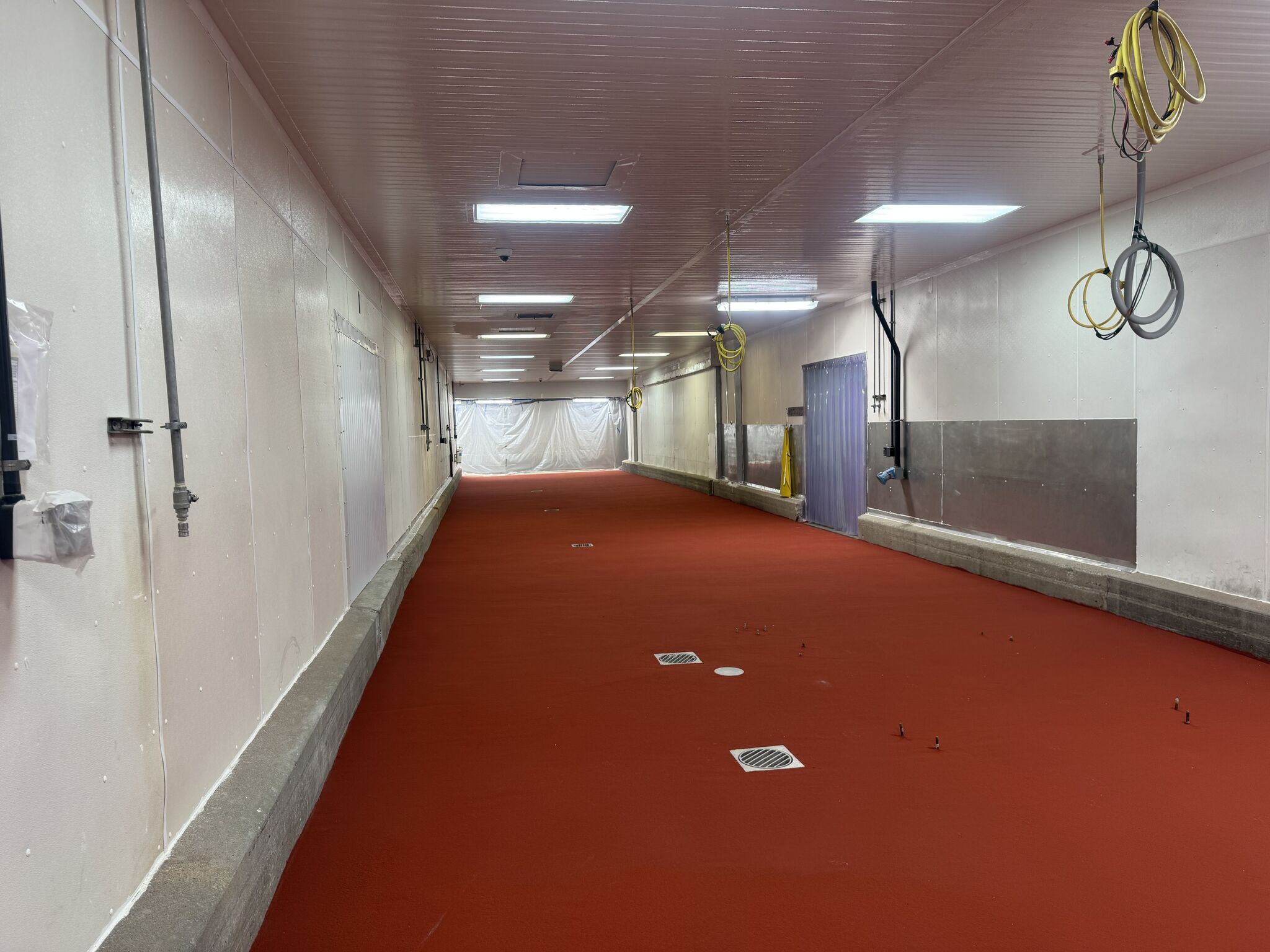 Finished SaniCrete STX floor in oven room hallway with floor drains and concrete curbs along walls