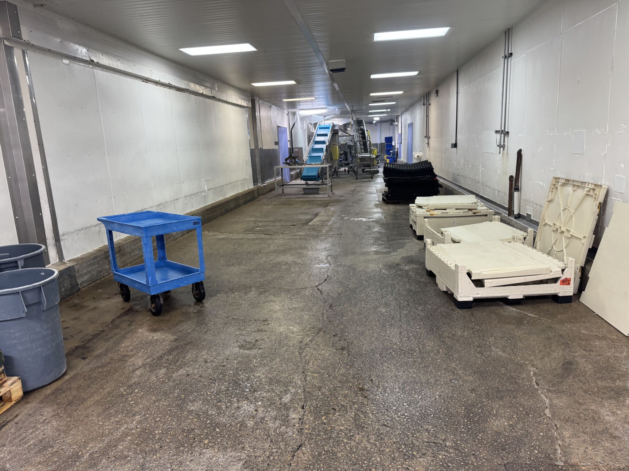 Uncoated concrete hallway in processing facility with equipment before flooring installation