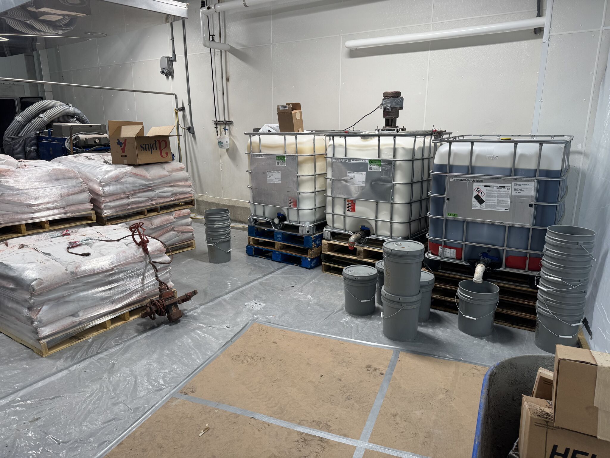 SaniCrete STX materials staged for installation including tote tanks, aggregate bags, and mixing supplies