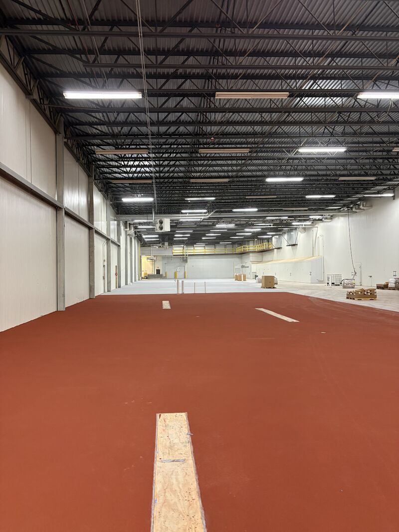 SaniCrete crew installing gray STX flooring in a new food processing expansion
