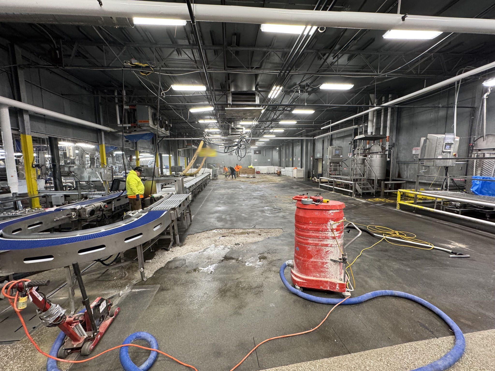 Production floor during preparation — conveyor belt, equipment, and hoses visible