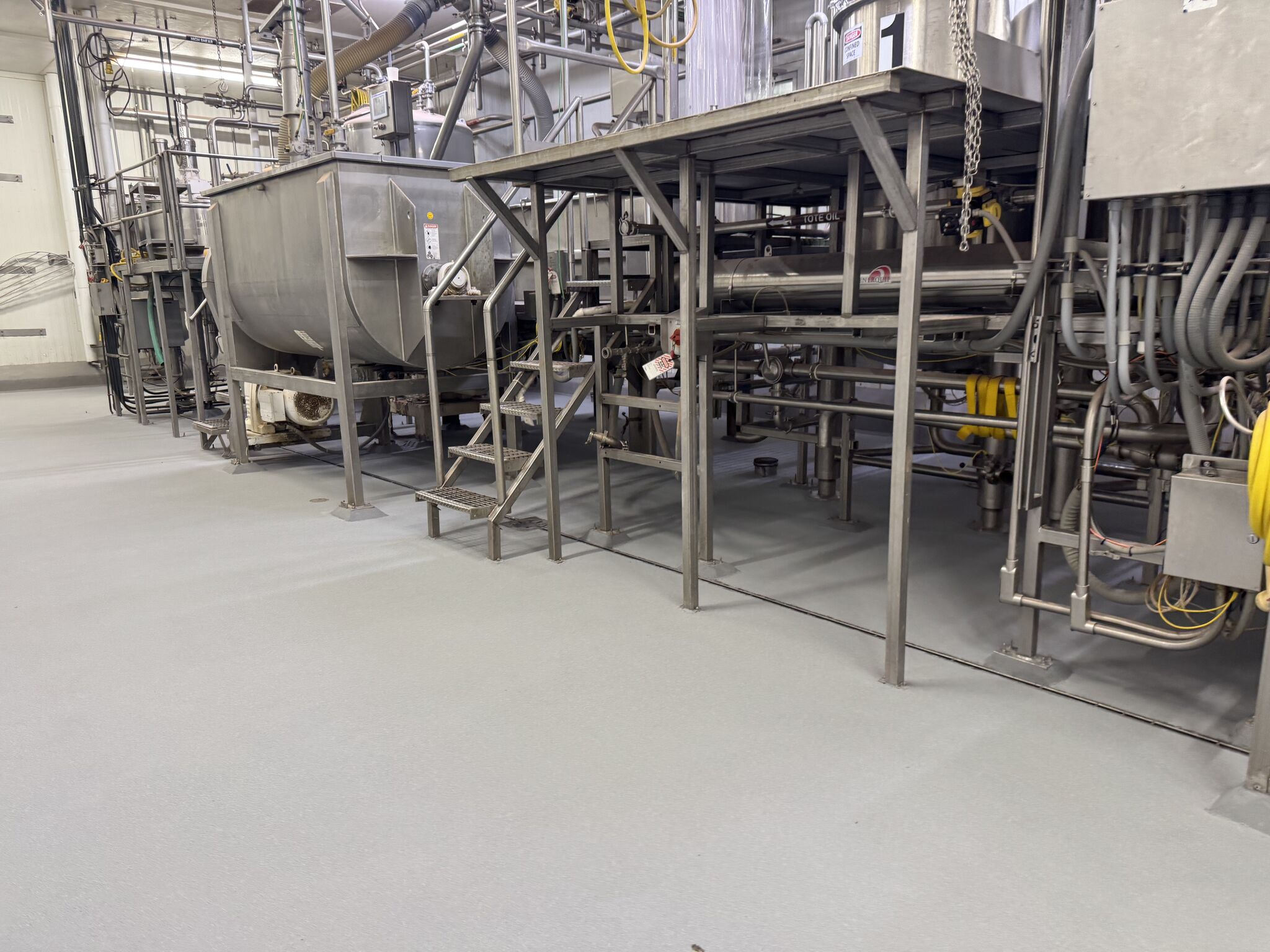 Completed — seamless floor under processing equipment with mixing tanks and conveyor system