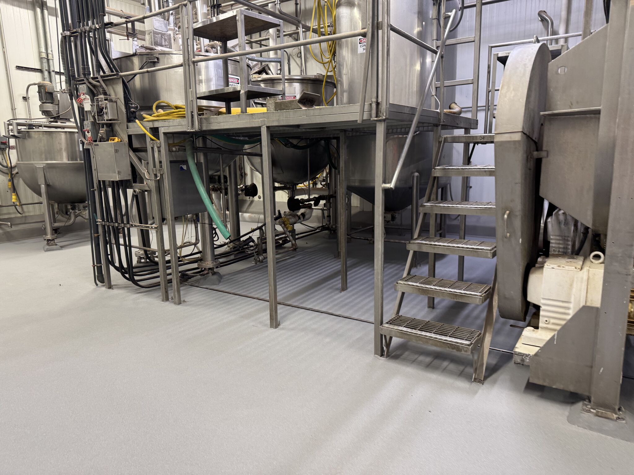Completed — wide view of production area with pristine gray STX floor, stairs, and equipment