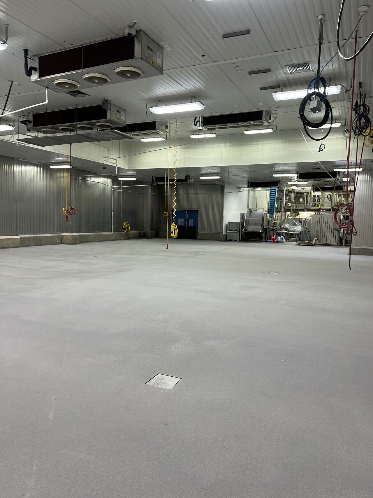Completed gray SaniCrete STX floor in large production room with evaporator fans and industrial equipment