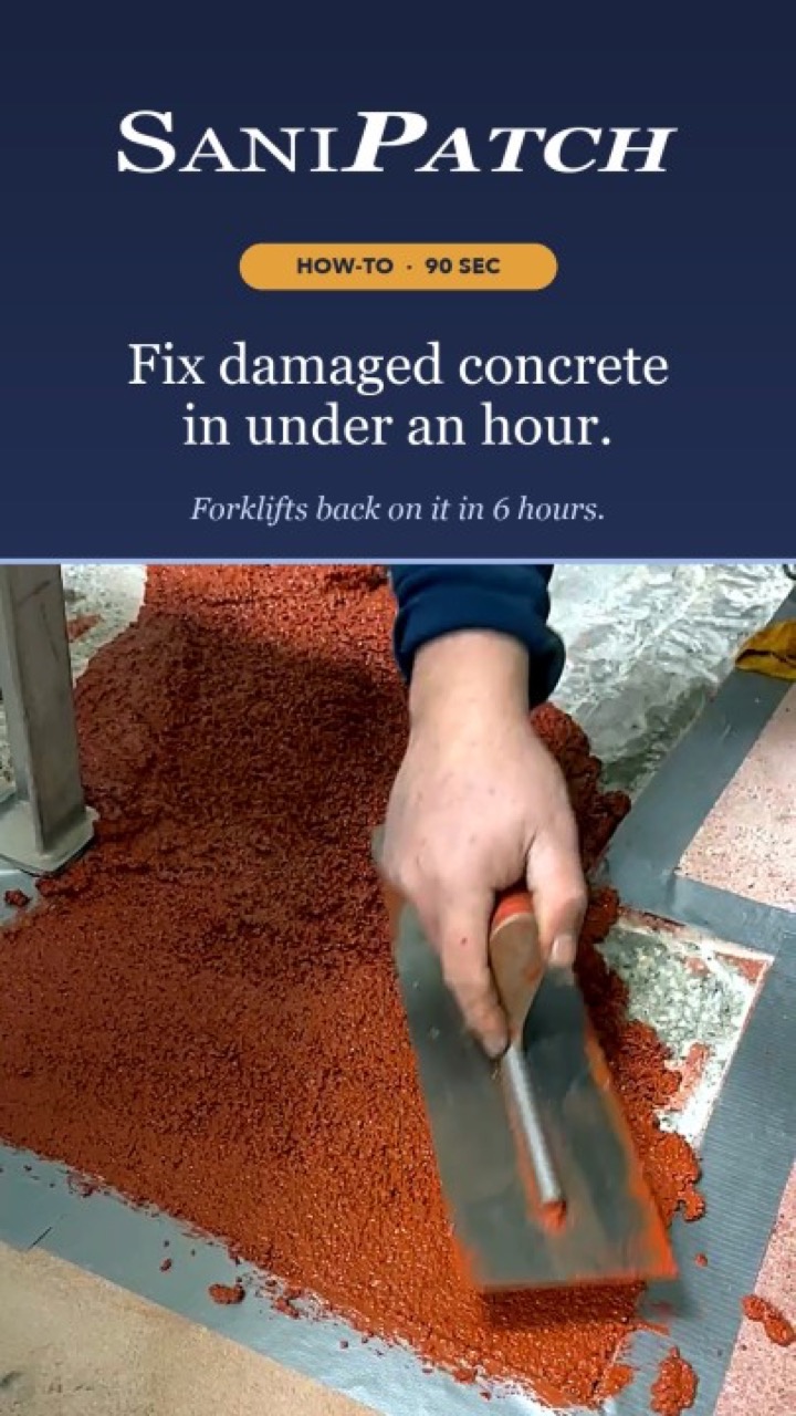 Worker troweling red SaniPatch polyurethane cement into a prepared and taped floor repair area
