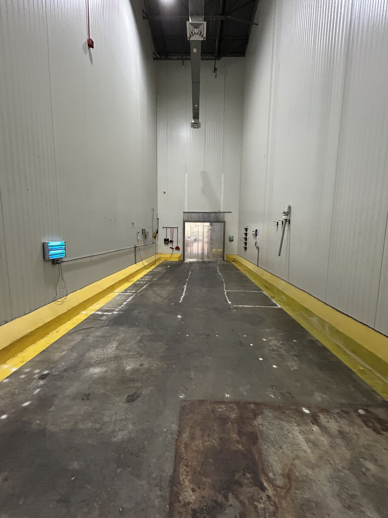 Spice room before renovation — worn dark floor with yellow curbing and surface damage