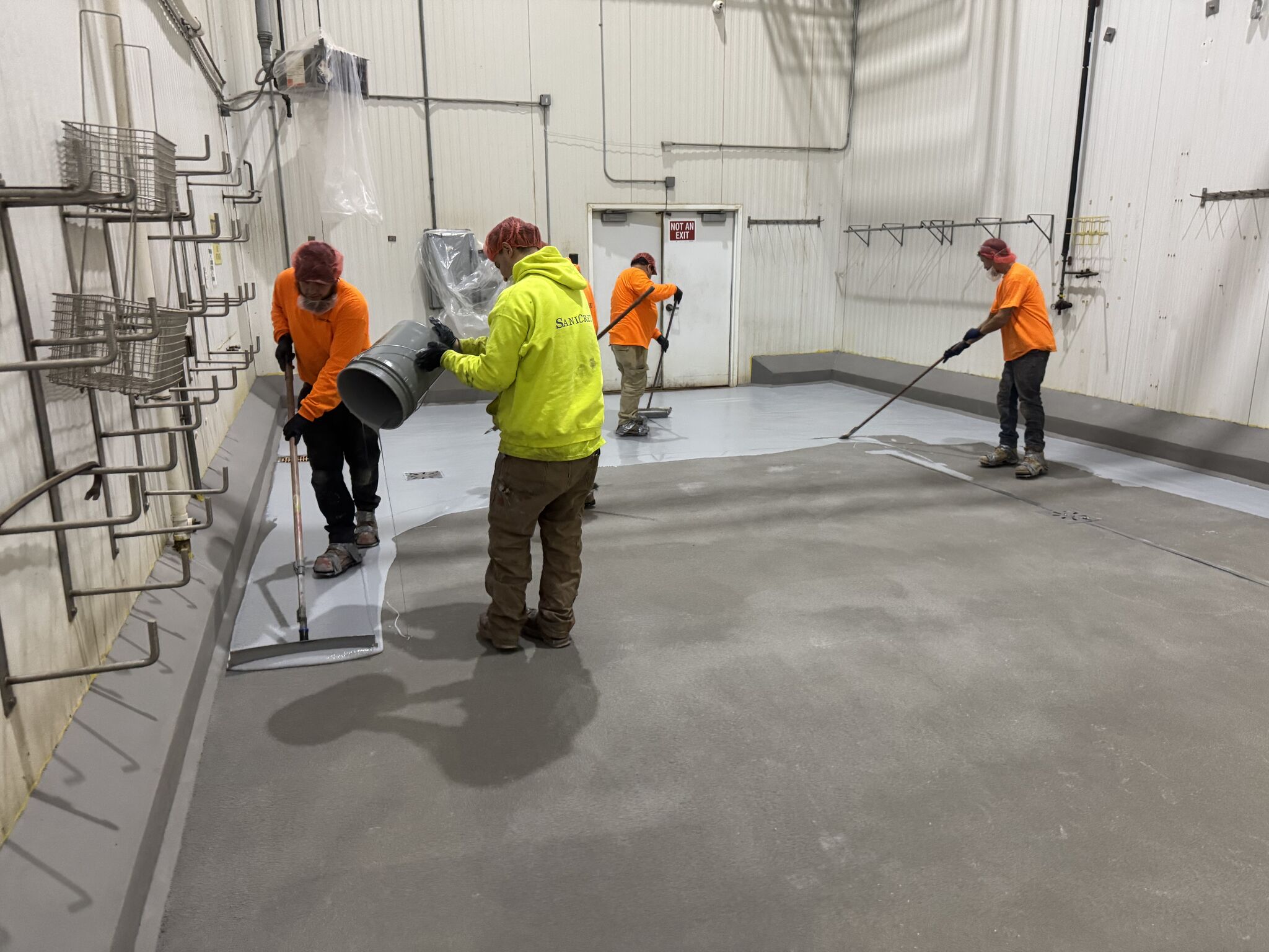 Full SaniCrete crew pouring and spreading cementitious urethane in chemical room