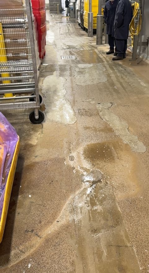 Patched wet food processing corridor floor before SaniCrete repair