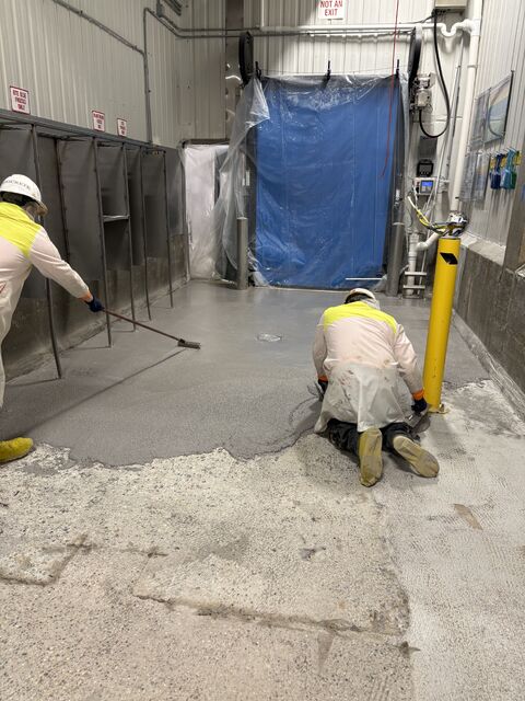 SaniCrete crew installing gray STX flooring in a food plant corridor